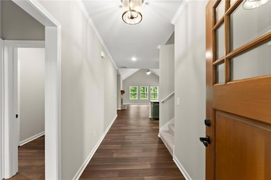 Hall with crown molding, vaulted ceiling, dark wood-style floors, and stairs