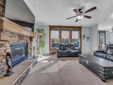 Unfurnished living room featuring a stone fireplace, ceiling fan, and carpet floors