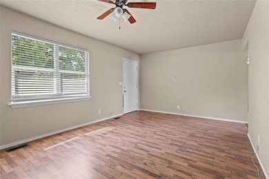 Empty room with a textured ceiling, wood finished floors, and ceiling fan