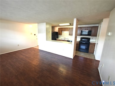 Unfurnished living room with dark wood-type flooring and a textured ceiling