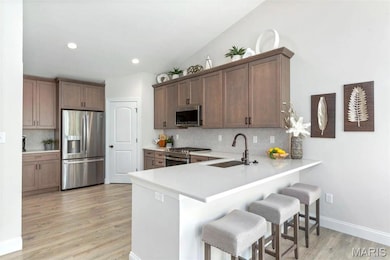 Kitchen with kitchen peninsula, appliances with stainless steel finishes, a breakfast bar, and light wood-type flooring
