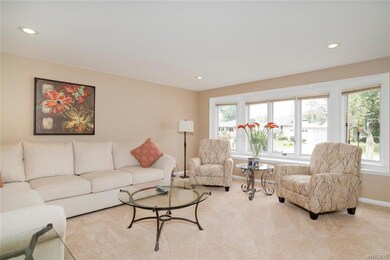 Living room features plush carpeting, recessed lig