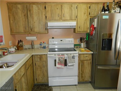 Kitchen featuring stainless steel appliances, light countertops, light tile patterned floors, range hood, and brown cabinetry