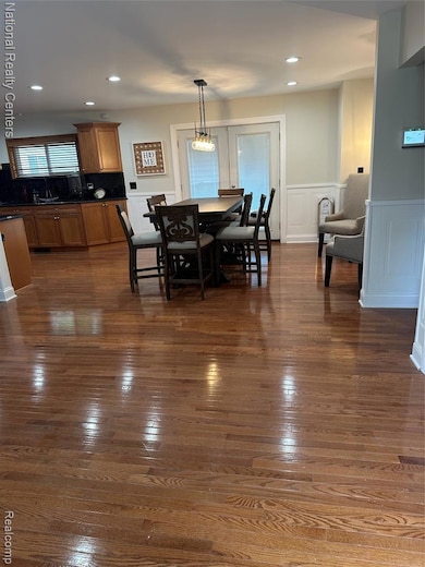 Dining area with dark wood-style floors, recessed lighting, a decorative wall, and a wainscoted wall