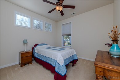 Carpeted bedroom with multiple windows and ceiling fan