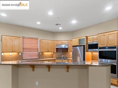 Kitchen with decorative backsplash, stainless steel appliances, recessed lighting, dark stone counters, and light brown cabinets
