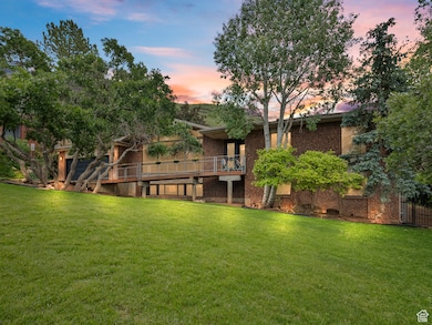 Front view of house featuring a lawn, brick siding, and a wooden deck