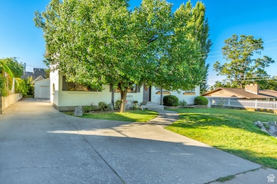 View of property hidden behind natural elements with brick siding, a garage, and concrete driveway