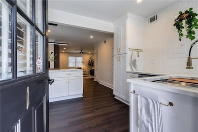 Kitchen with white cabinets, dark wood finished floors, recessed lighting, a sink, and a peninsula