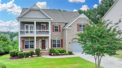 Craftsman-style home with a balcony, concrete driveway, a front lawn, and brick siding