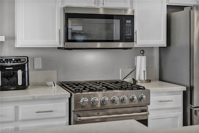 Kitchen with white cabinetry, appliances with stai