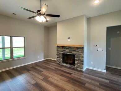 Unfurnished living room with dark wood finished floors, a fireplace, and ceiling fan