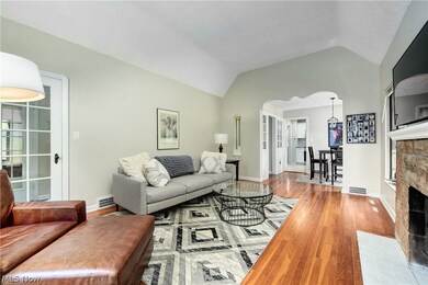 Living room featuring a fireplace, vaulted ceiling, and hardwood floors