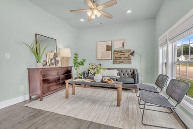 A spacious front living room is grand with high ceilings and large windows with natural light ~