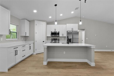 Kitchen sink and dishwasher are in the island with large amounts of quartz countertop for meal prep, and a corner pantry with an 8 foot door