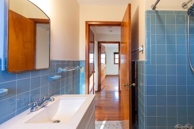 Bathroom featuring tile walls, vanity, a wainscoted wall, and light wood-type flooring