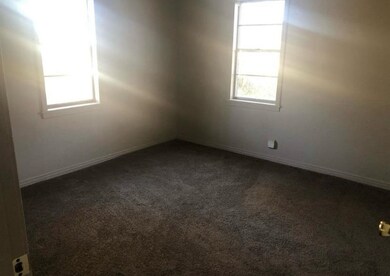 Empty room with dark carpet and baseboards