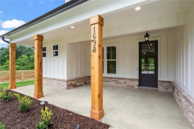 View of exterior entry with board and batten siding, covered porch, and brick siding