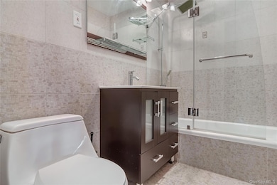 Bathroom featuring tile walls, vanity, and tiled shower / bath combo