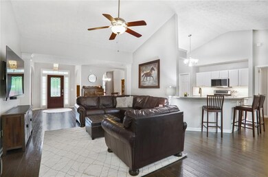 Family room with cathedral ceiling, with view to the new Mahagony-stained front door with decorative glass window, hard wood floors, and ceiling fan