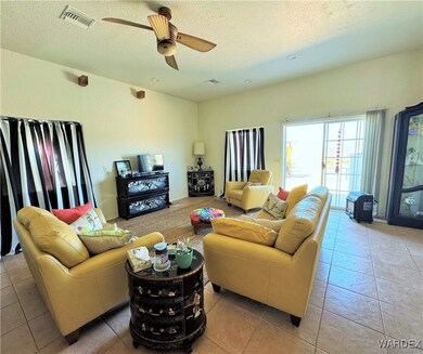 Living area featuring light tile patterned floors, visible vents, a textured ceiling, and ceiling fan