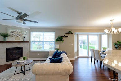 Living room with crown molding, dark wood-style floors, healthy amount of natural light, a chandelier, and a tiled fireplace