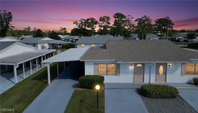 View of front of home featuring driveway, roof with shingles, a residential view, and an attached carport