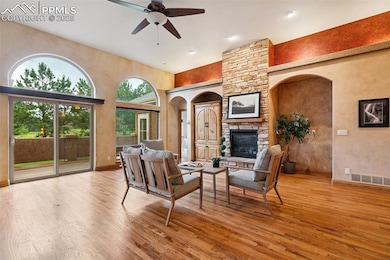 Living area featuring plenty of natural light, a fireplace, a ceiling fan, hardwood flooring, and a towering ceiling