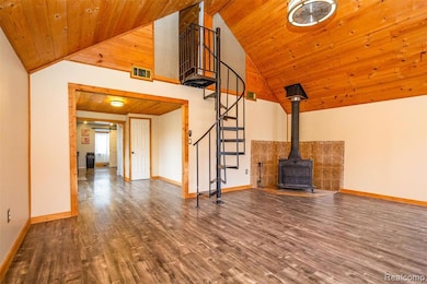 Unfurnished living room featuring a wood stove, dark wood finished floors, wooden ceiling, stairs, and high vaulted ceiling