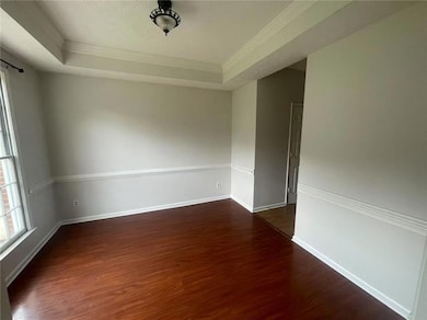 Unfurnished room with wood finished floors, crown molding, and a raised ceiling