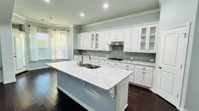 Kitchen with a sink, white cabinets, a kitchen island with sink, and under cabinet range hood