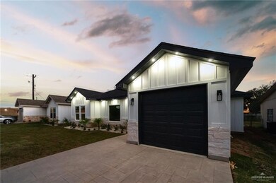 View of front of property featuring board and batten siding, a garage, stone siding, a front yard, and decorative driveway