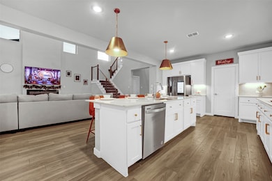 Kitchen with a kitchen breakfast bar, hanging light fixtures, white cabinets, open floor plan, and a kitchen island with sink