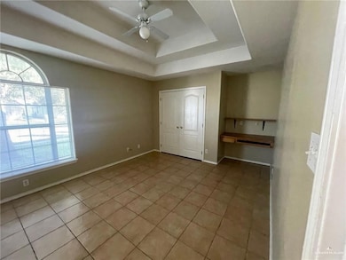 Unfurnished bedroom featuring light tile patterned floors, a tray ceiling, a closet, and ceiling fan