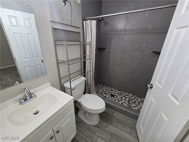 Bathroom featuring vanity, a stall shower, wood finish floors, and a textured wall