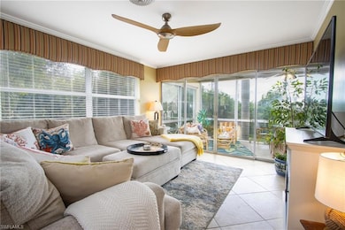 Living room with ceiling fan, crown molding, and light tile patterned floors