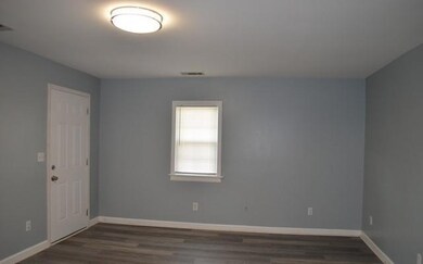 Spare room featuring dark wood-type flooring and baseboards
