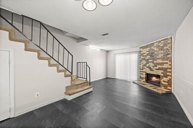 Unfurnished living room with stairs, a textured ceiling, and a brick fireplace