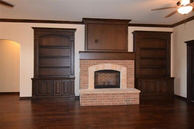 Unfurnished living room featuring ceiling fan, wood finished floors, ornamental molding, baseboards, and a fireplace