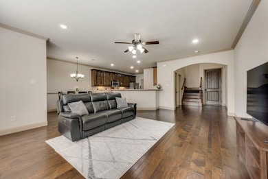 Living room featuring stairway, recessed lighting, dark wood finished floors, a chandelier, and crown molding