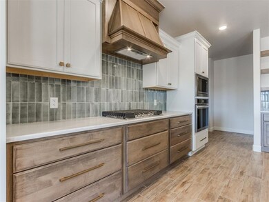 Kitchen featuring custom exhaust hood, light wood-