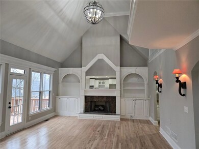 Unfurnished living room with light hardwood / wood-style flooring, a towering ceiling, ornamental molding, and a notable chandelier
