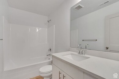 Full bath with bathing tub / shower combination, vanity, and light wood-style flooring