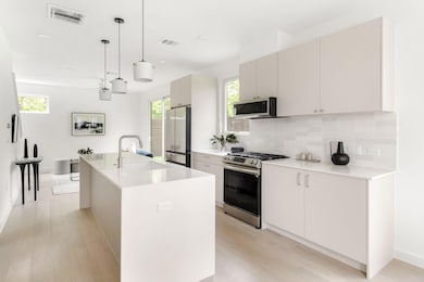 Kitchen featuring light wood finished floors, stainless steel appliances, visible vents, and a sink