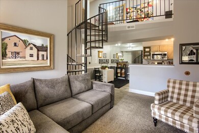 Living room featuring stairs, light colored carpet, and a towering ceiling