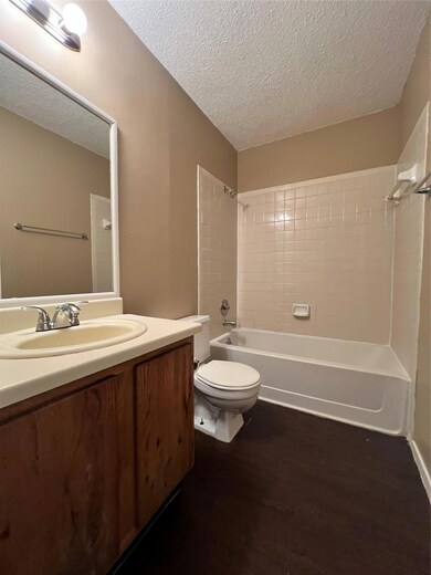 Bathroom featuring a textured ceiling, vanity, ba
