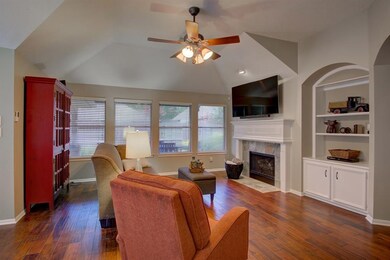 Living room with wood flooring built ins, ceiling fan and gas log fireplace