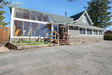View of front with stone siding, a sunroom, gated fence to backyard