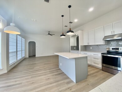 Kitchen featuring arched walkways, stainless steel range with electric stovetop, backsplash, open floor plan, and a ceiling fan