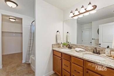 Bathroom featuring double vanity, shower / bathtub combination with curtain, tasteful backsplash, and a closet